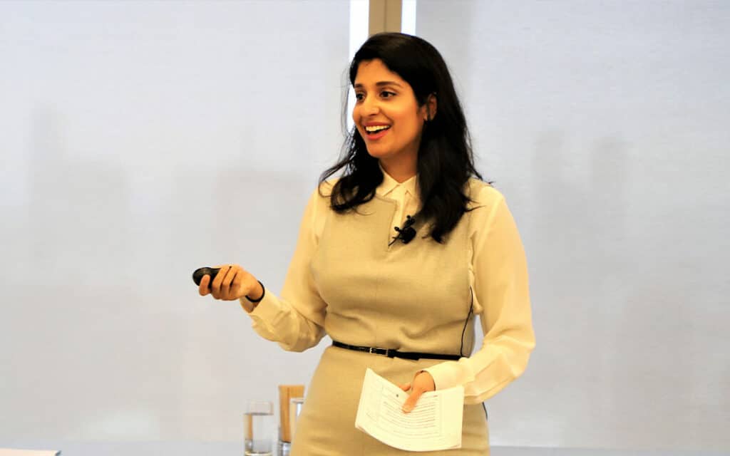 Dr. Komal Bhasin in a bright conference room presenting a keynote speech