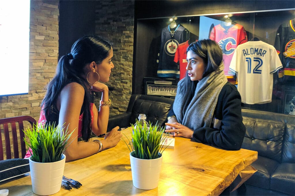 Ritu Bhasin seated across a table from a young women in conversation