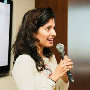 Dr. Komal Bhasin speaking into a handheld microphone while teaching a workshop