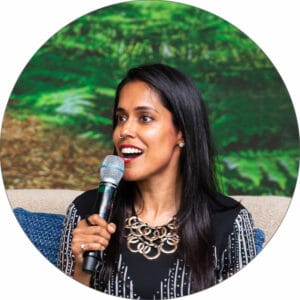 Ritu Bhasin sits in a chair holding a microphone