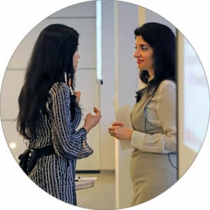 Ritu Bhasin and Dr. Komal Bhasin standing together in a conference room having a conversation