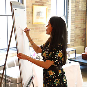 Profile view of Ritu Bhasin in a conference room writing on a flip chart with a marker